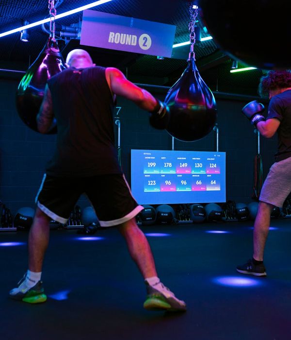 Man performing a dynamic strength exercise in a minimalist dark gym.